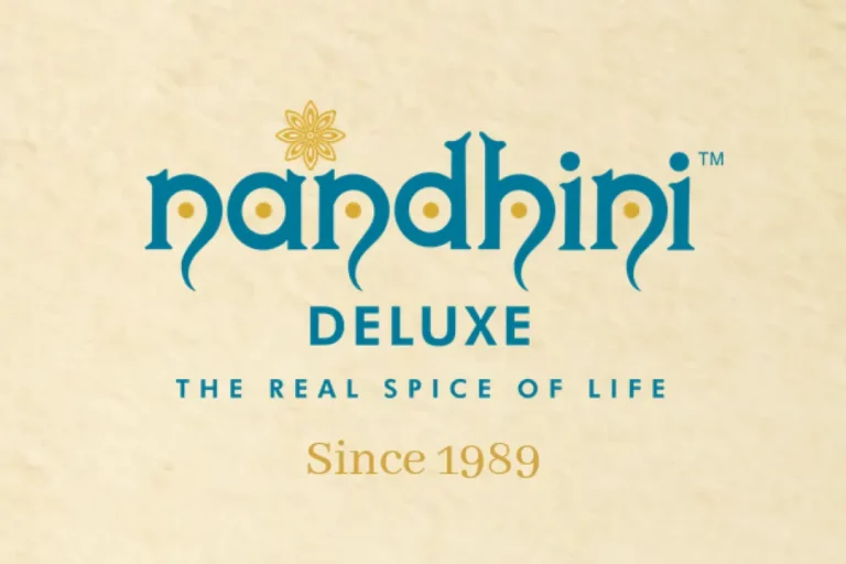 The Nandhini Deluxe logo in teal and gold on a cream background, with the tagline "The Real Spice of Life" and "Since 1989."