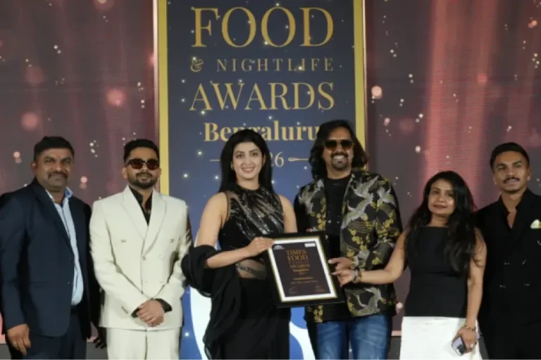 The Nandhini Deluxe team receiving the Times Food and Nightlife Awards Bengaluru 2026 framed certificate on stage.