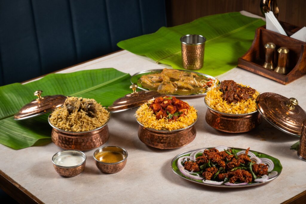 Nandhini Deluxe Andhra biryani served in copper handis with raita, gravy and a chicken starter